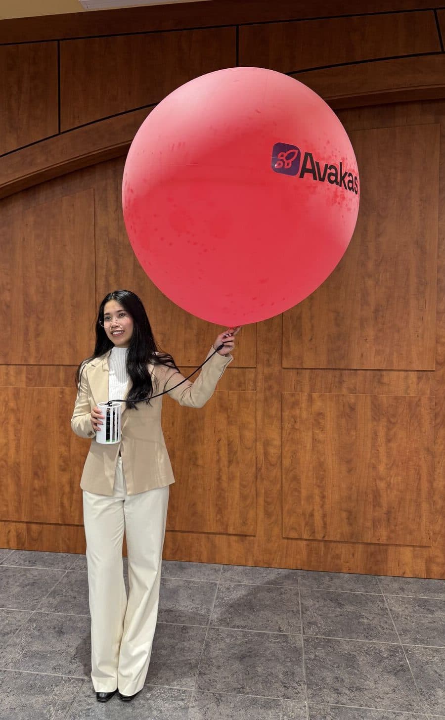 SooAh Lay holding an Avakas-branded launch balloon, the CanSat clipped to its tether.